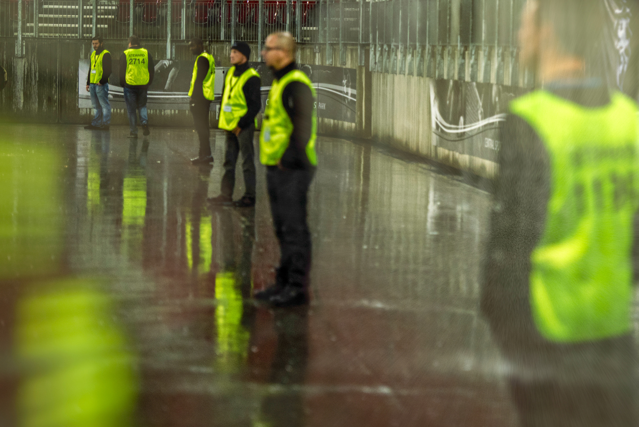 Security employees standing in a line at a stadium on a sporting event at night.